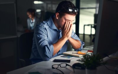 Employee working late at night in an empty office, looking frustrated and exhausted.
