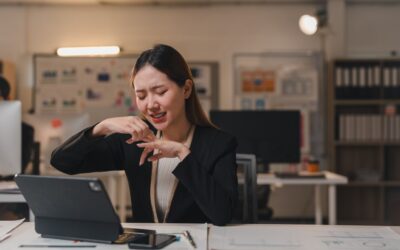 Frustrated employee sitting alone at desk with finger bandaged.
