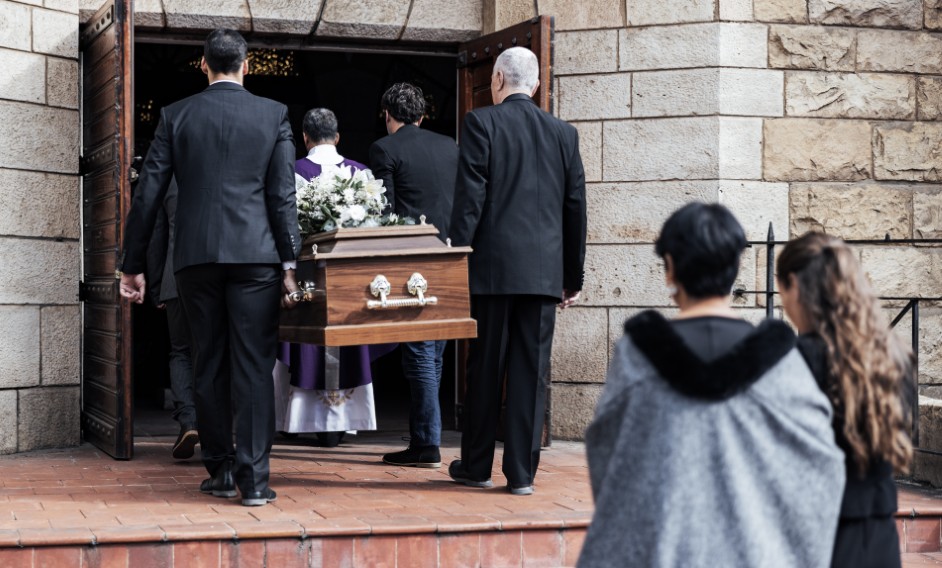 Employee receiving paperwork outside a funeral home, appearing concerned and disappointed.