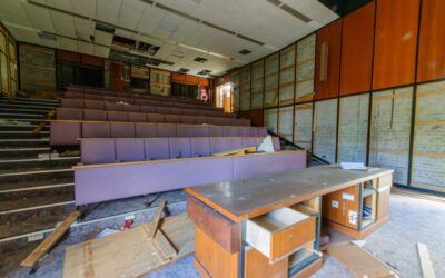 Empty lecture hall with overturned chair and scattered papers symbolizing professional chaos.