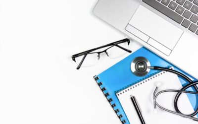 A closed laptop, a doctor’s note, and a pair of glasses on a desk symbolize a worker on medical leave.