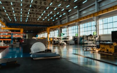 Factory floor with empty workstations and overhead lights casting shadows.
