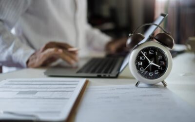 Employee reviewing paperwork with a worried look while a clock ticks in the background.