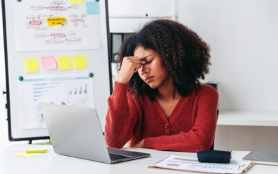 Employee sitting at a desk looking uneasy as an HR email notification appears.