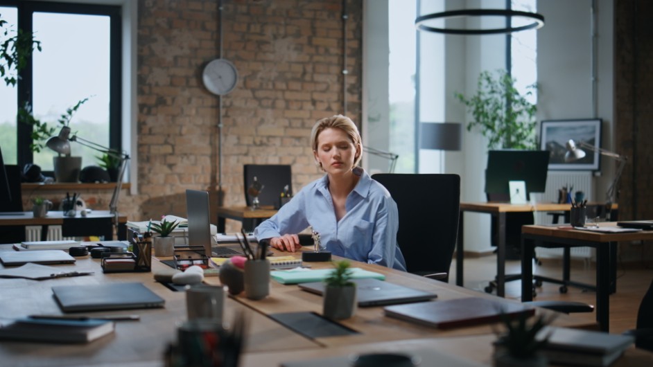 An employee sitting in an empty office holding an unfair performance review after being wrongfully fired.