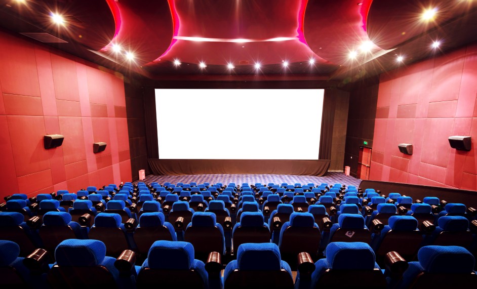 Empty movie theater hallway with marquee lights and rows of seats.