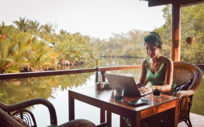 Remote worker abroad using a laptop while reviewing a job posting with updated requirements.
