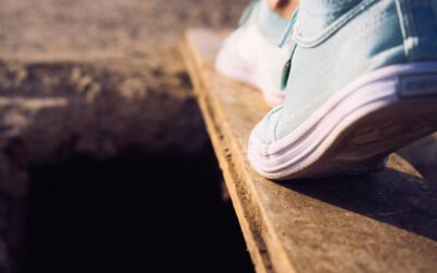 A person stepping carefully across a floor with hidden trap doors representing legal pitfalls.