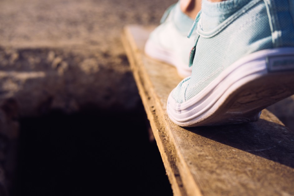 A person stepping carefully across a floor with hidden trap doors representing legal pitfalls.