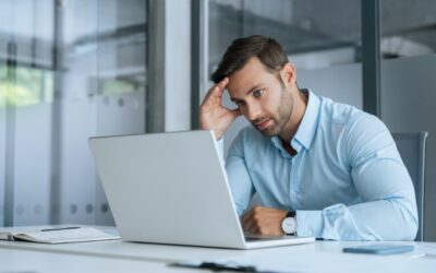 A stressed employee looking at a laptop while managing family medical responsibilities.
