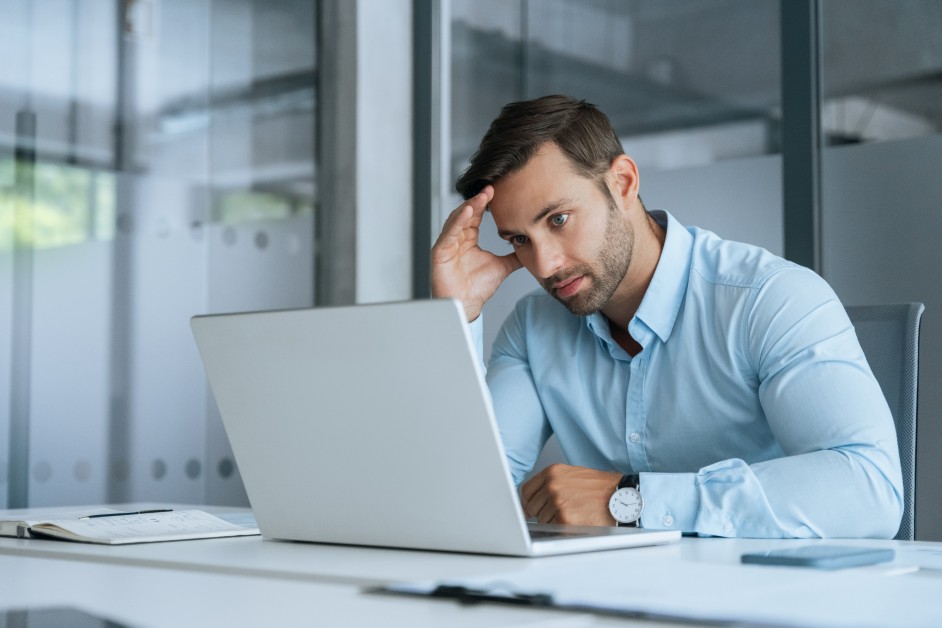 A stressed employee looking at a laptop while managing family medical responsibilities.