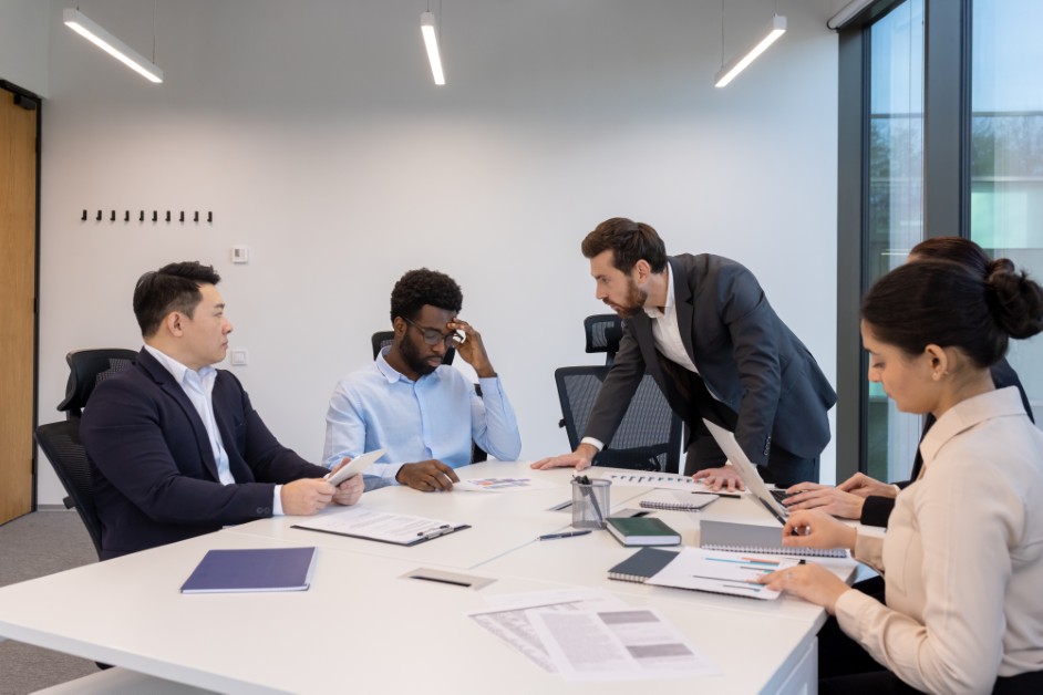 Employee in a tense meeting with supervisors, symbolizing whistleblower pressure and retaliation.