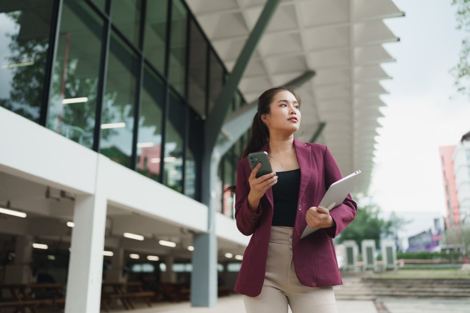 A professional woman standing outside a university building looking determined after being passed over for a leadership position.