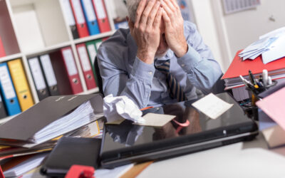 Employee sitting at an office desk with medical paperwork and a calendar, symbolizing disability accommodation and essential duty conflicts at work.