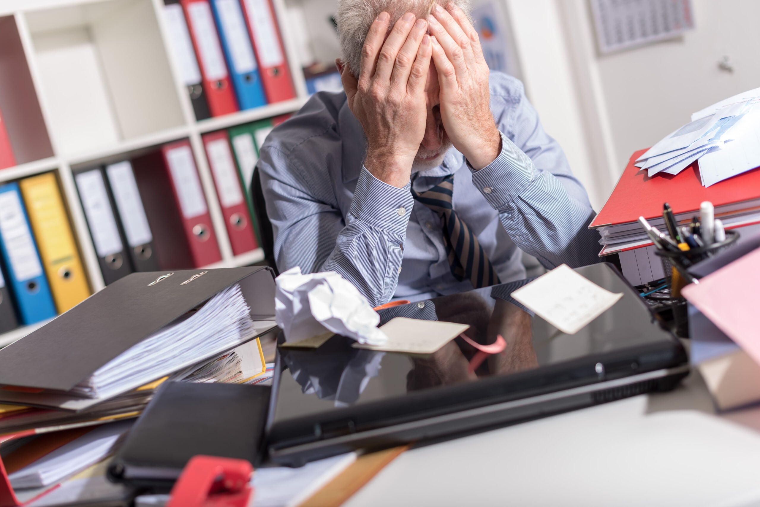 Employee sitting at an office desk with medical paperwork and a calendar, symbolizing disability accommodation and essential duty conflicts at work.