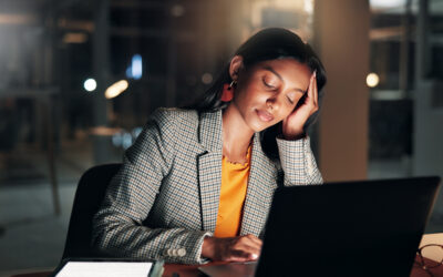Tired employee working late at a desk with a glowing clock showing unpaid overtime hours.