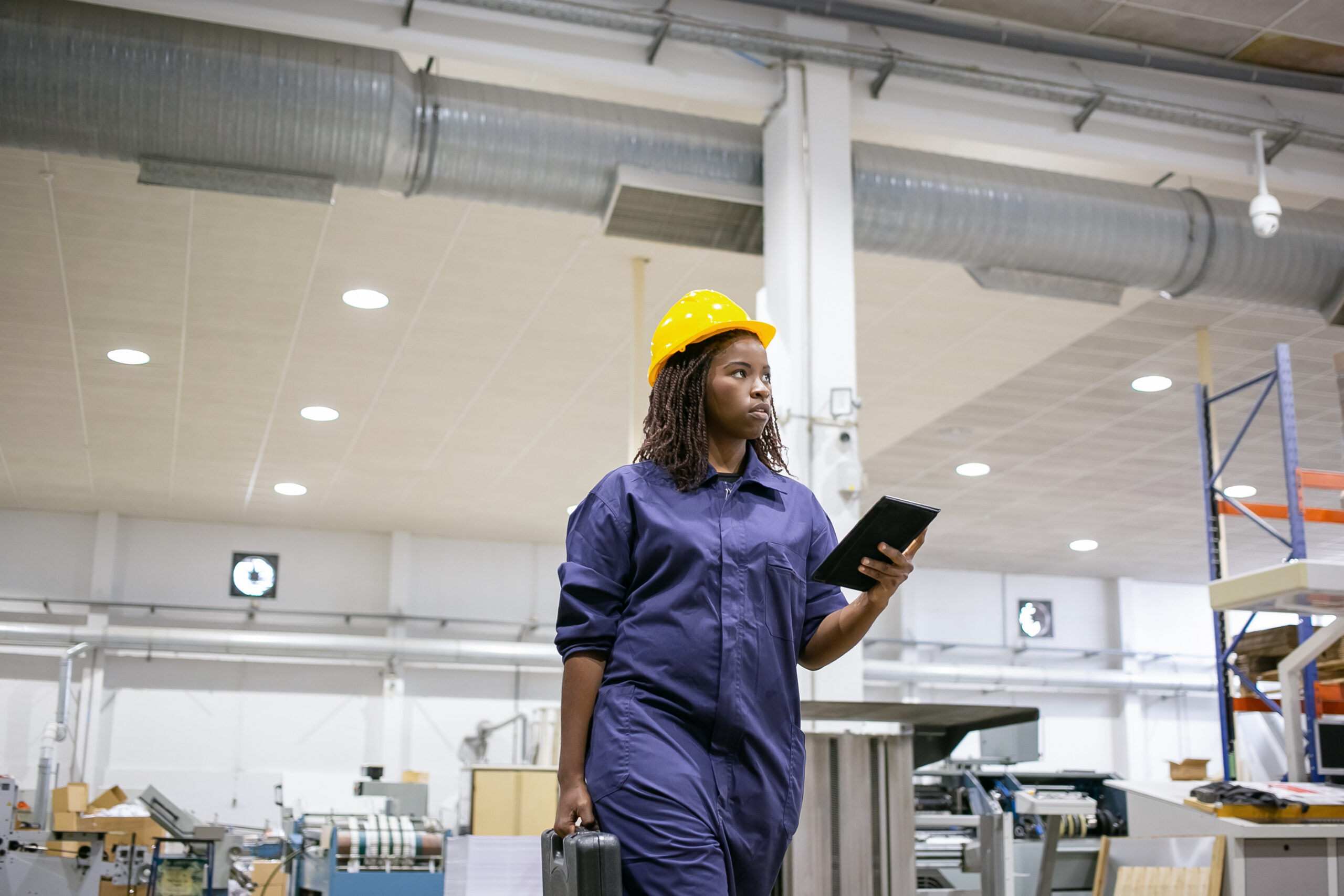 Factory supervisor walking production floor in protective gear