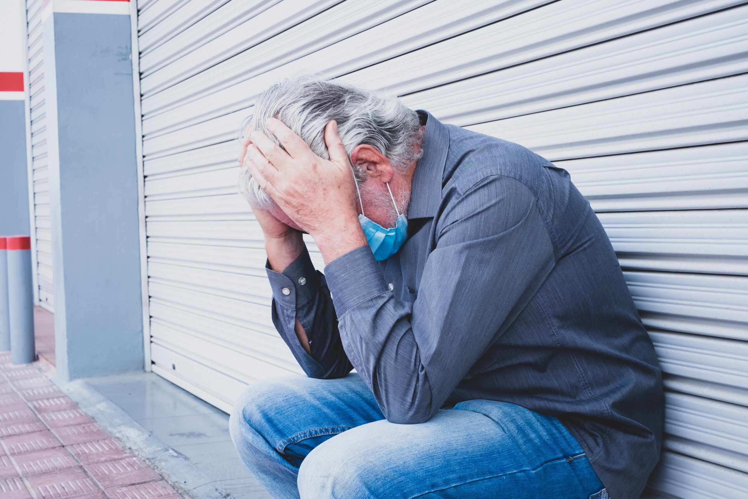 Older factory employee sitting alone after being terminated from job 