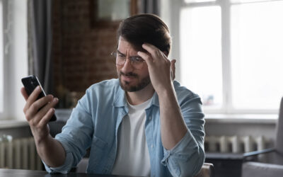 Employee staring at phone after returning from medical leave, reading a tense message from employer.