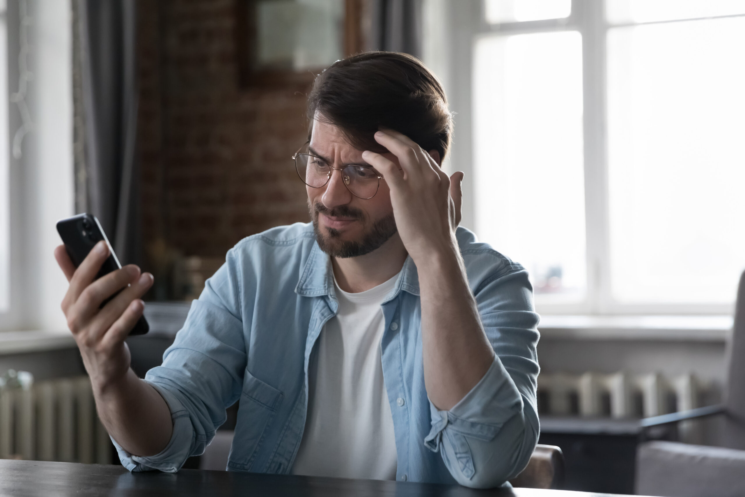 Employee staring at phone after returning from medical leave, reading a tense message from employer.