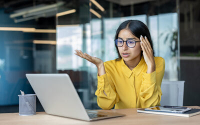 Employee sitting at desk looking frustrated after workplace conflict, representing discrimination and wrongful termination