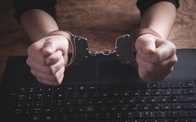 Former employee holding a company laptop outside an office building while a police vehicle waits nearby