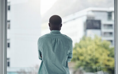 Factory employee standing alone after learning of a racial comment at work, reflecting isolation and workplace discrimination