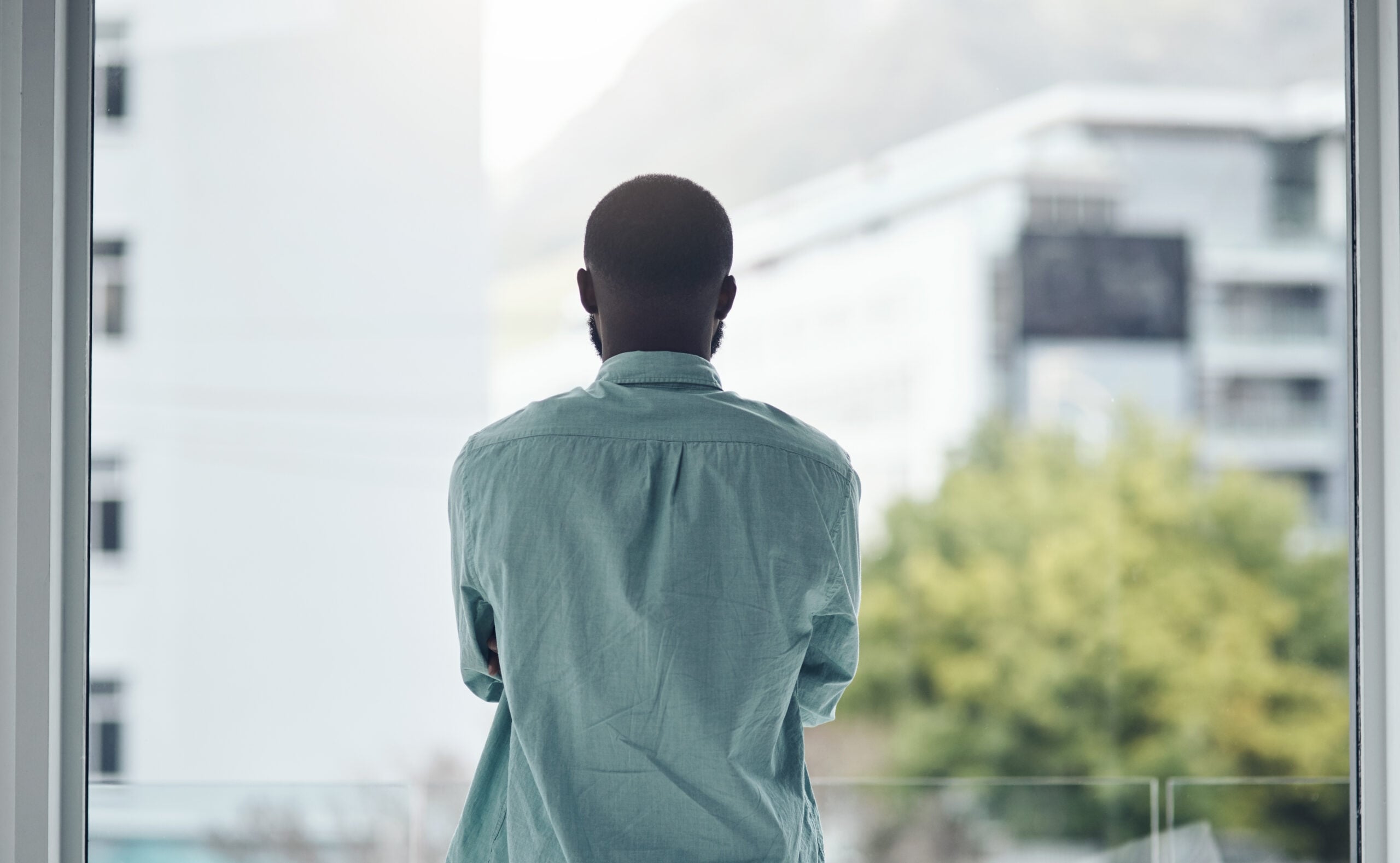 Factory employee standing alone after learning of a racial comment at work, reflecting isolation and workplace discrimination 