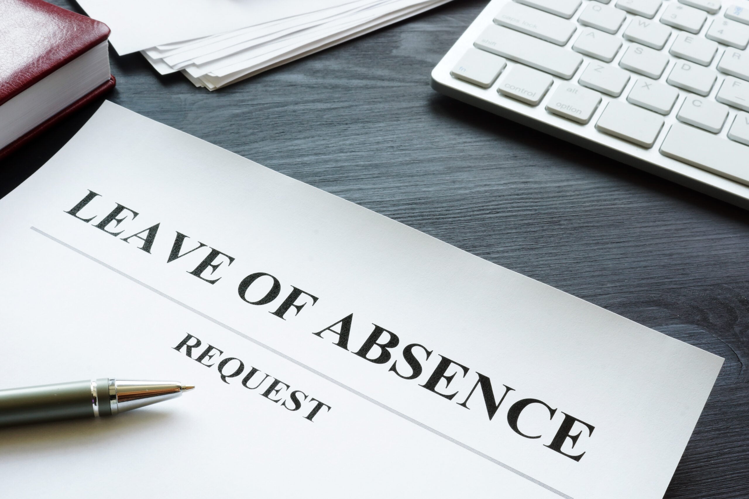 Employee reviewing unpaid medical leave, FMLA paperwork, ADA accommodation forms, and household bills at a kitchen table