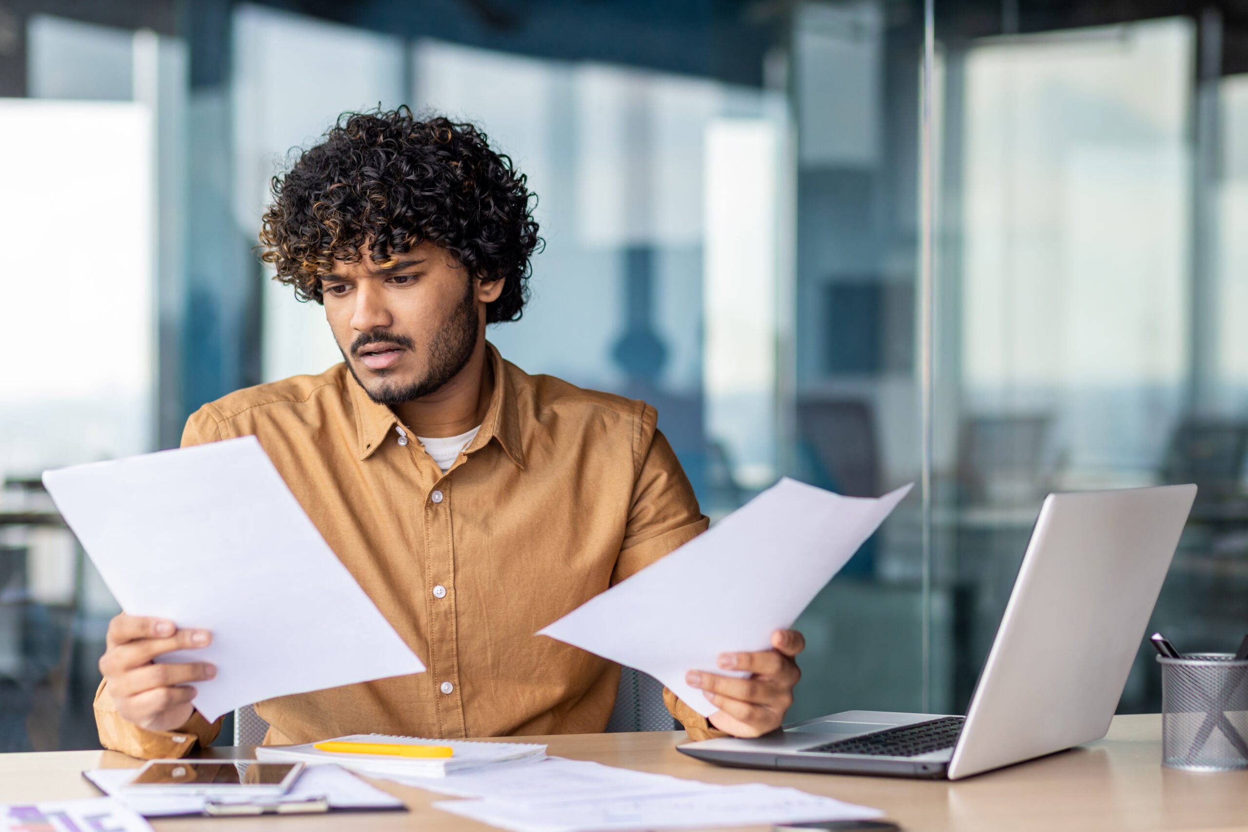 Confused employee reviewing FMLA paperwork, medical leave forms, and employment law documents after workplace stress. 