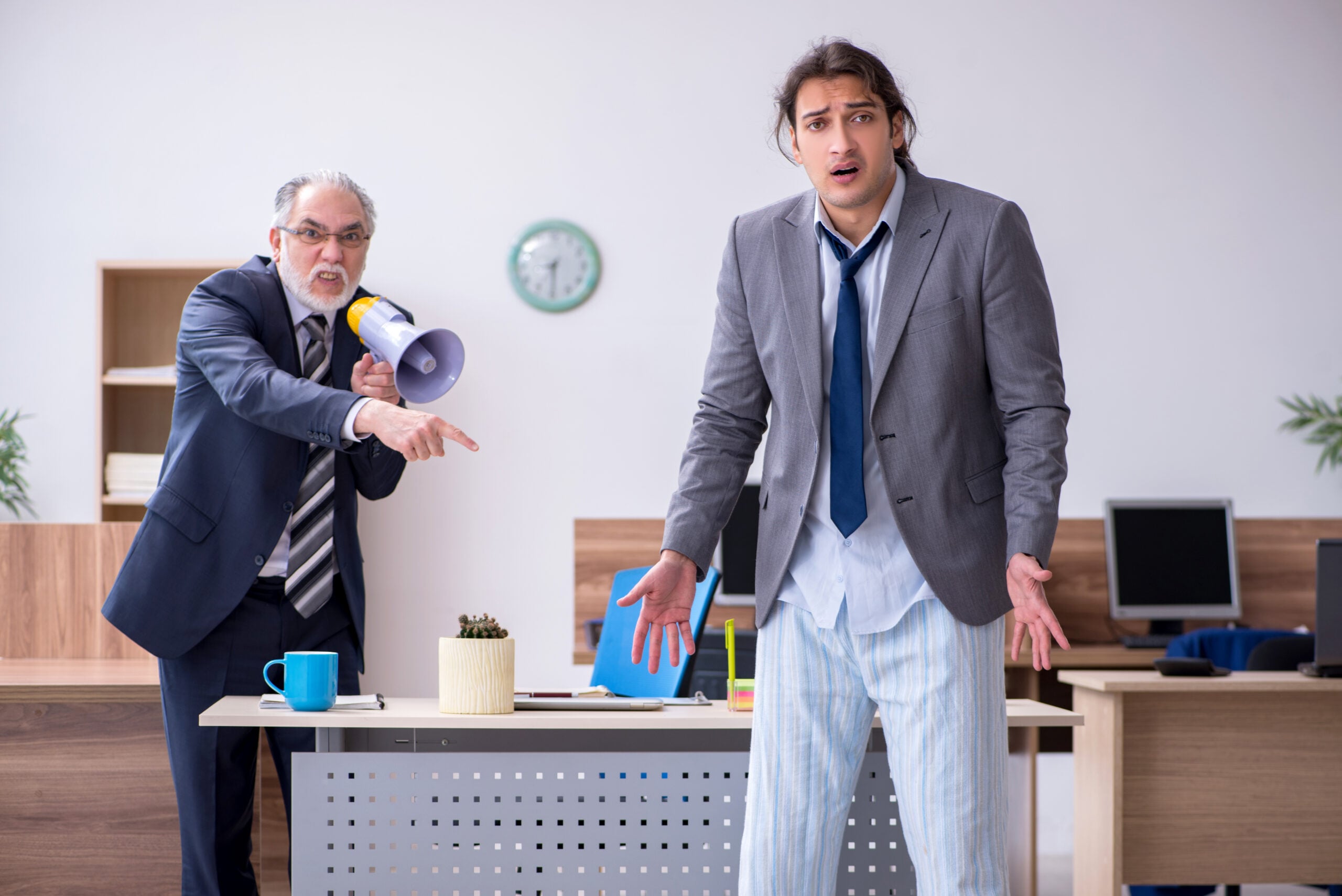 Employee sitting silently while an angry supervisor publicly criticizes the employee during a workplace meeting, illustrating the difference between workplace bullying and unlawful discrimination.
