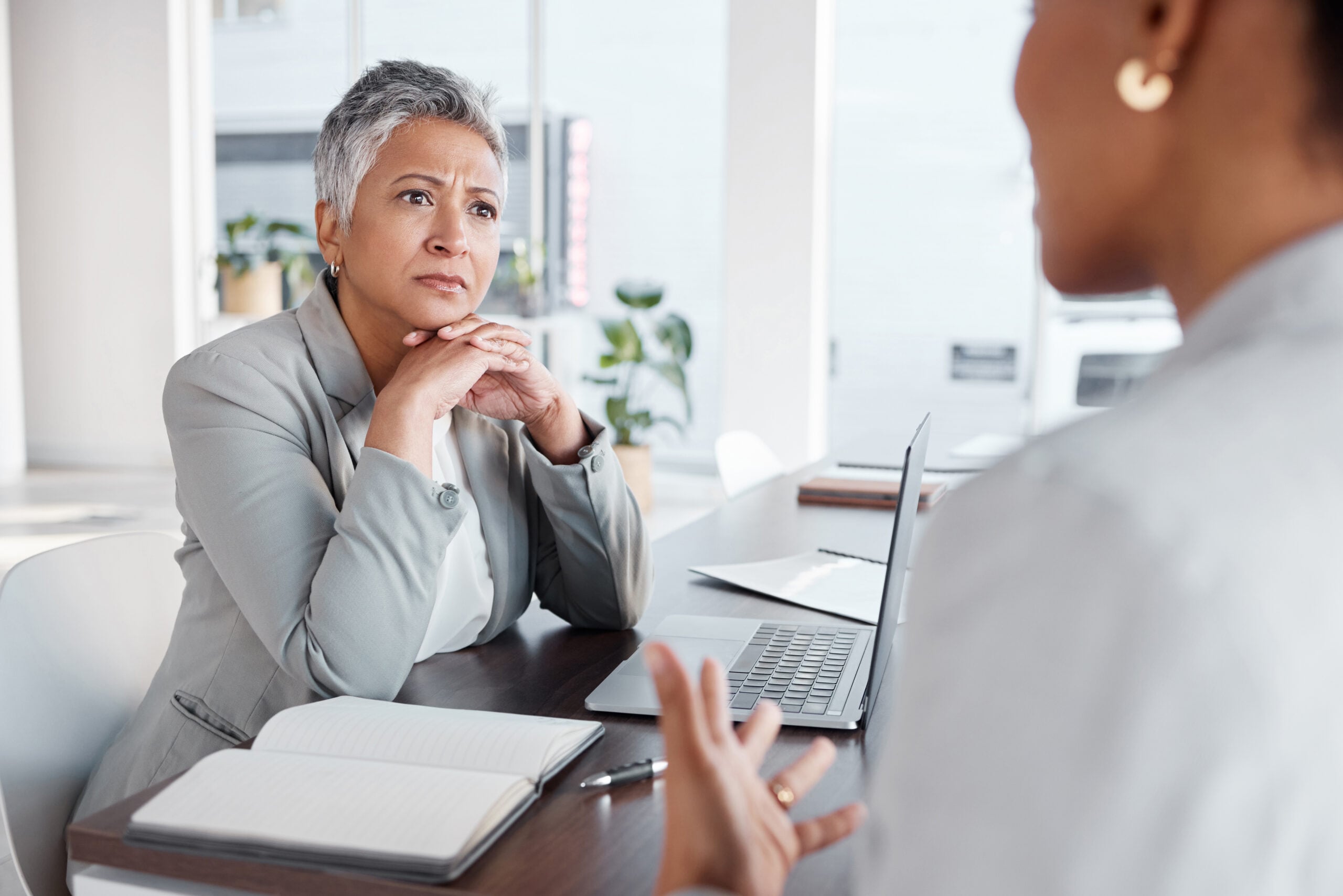 Employee speaking during a workplace meeting about race-based employment practices while managers react, illustrating Title VII retaliation and affirmative action disputes.