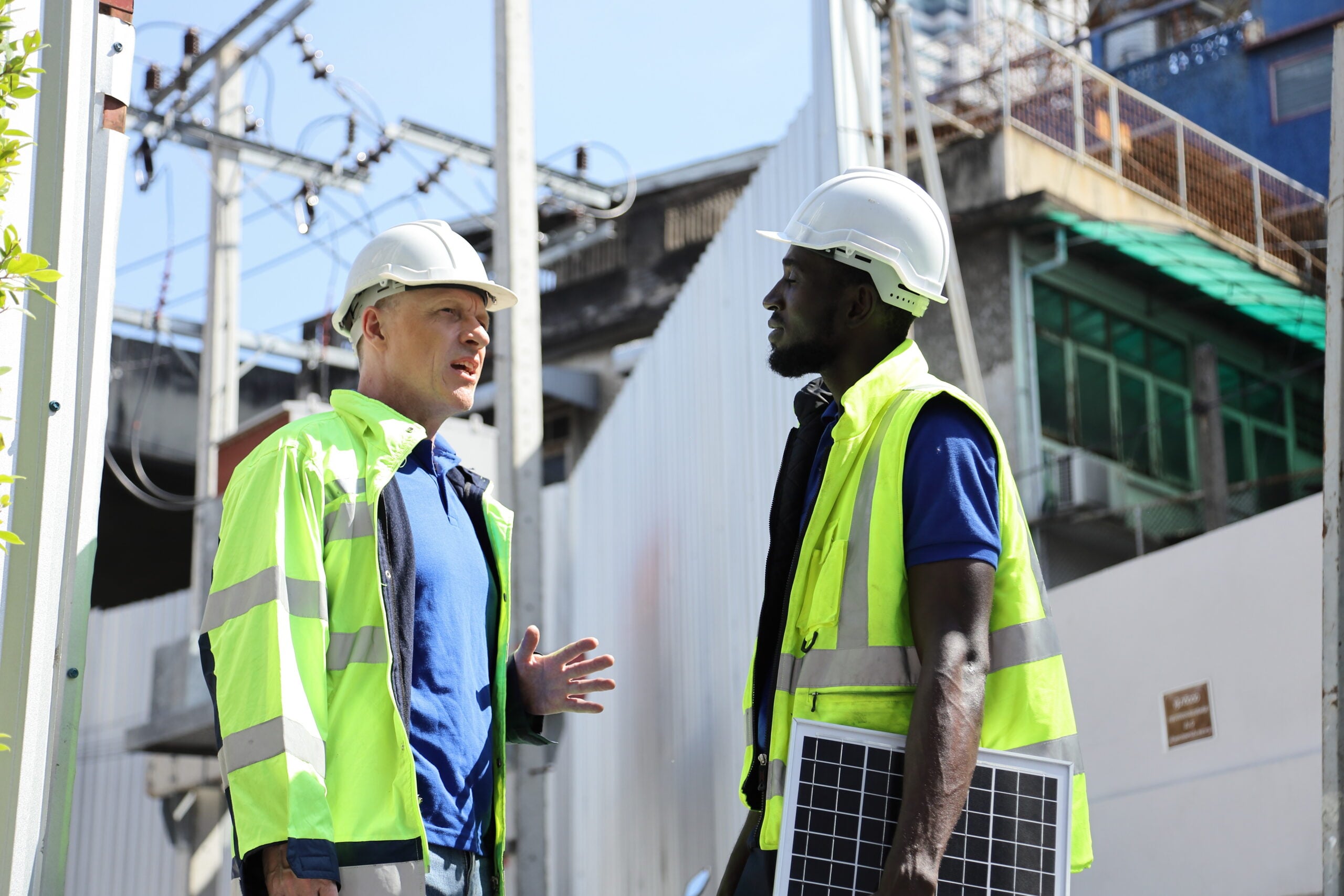 Black and white construction employees working together at an industrial jobsite.