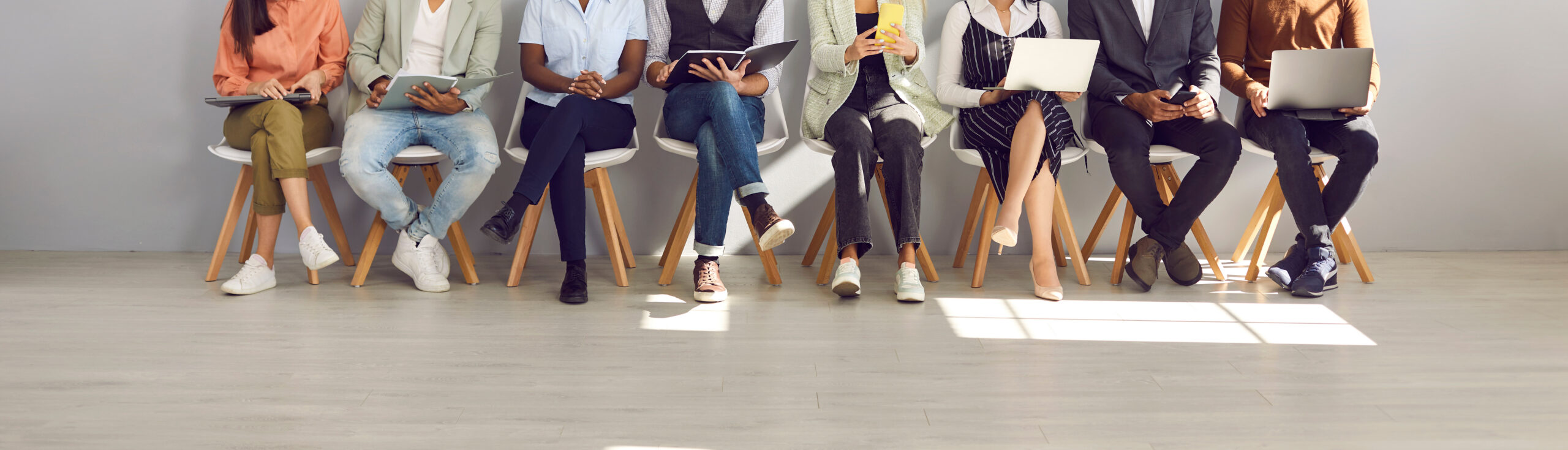 Diverse group of job candidates waiting outside an interview room during a hiring process.